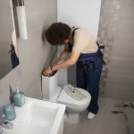 fontanera arreglando un sanitario en una casa